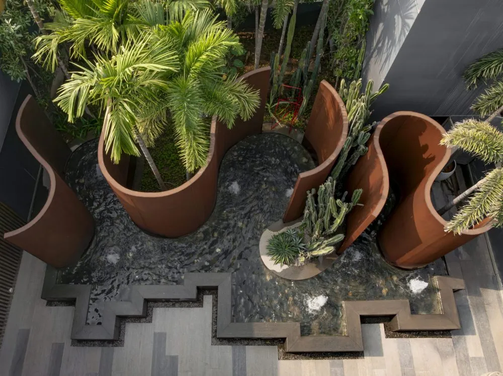 Looking down on corten planters full of palms and cacti, set in black pebbles.