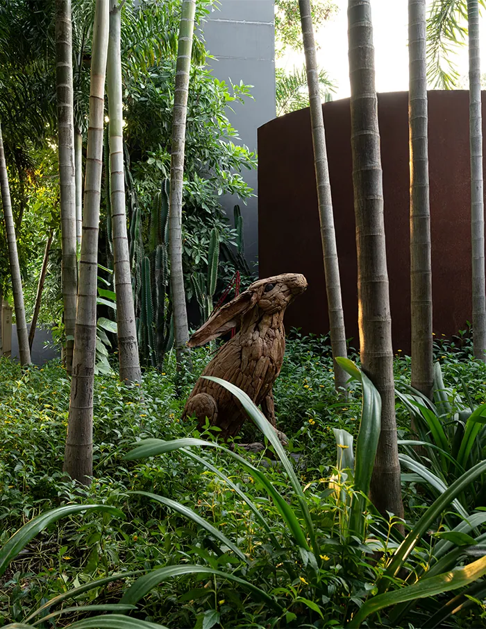 Dense green planting and tall bamboo in front of a curved corten wall.