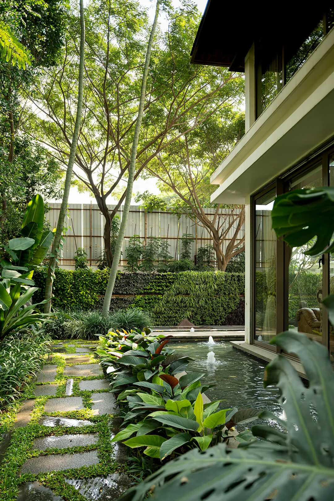 Stepping stones lead through planting past a small fountain beside the house.